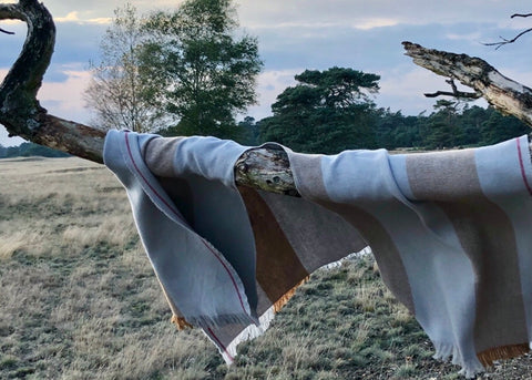 DETAIL OF DETAIL OF PONCO GUARDA, MADE IN TWO BEAUTIFUL COLORS; CLASSICAL BEIGE AND PALE BLUE. THE PONCHO IS MADE IN 50% BIO COTTON, 50% BIO WOOL. THE PONCHO HAS A RED LISTING, AND A BEAUTIFUL STAMP EMBROIDERED IN RED ON THE LEFT FRONT PANEL (FOR THE WEARER)