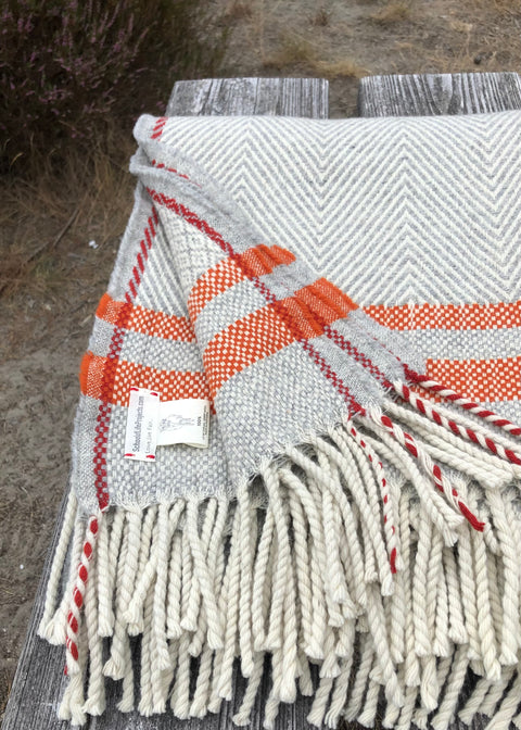 A detail of our 100% bio woolen blanket Serra da Estrela, 4 colors; wool white (the natural white of the wool, heather grey, burnt orange and a hint of red, as we are huge denim lovers, the red detail suggests the selvedge detail on quality denims. 