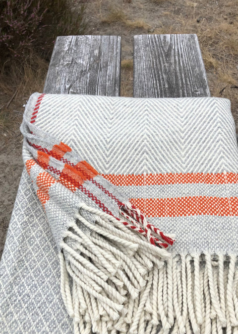 A detail of our 100% bio woolen blanket Serra da Estrela, 4 colors; wool white (the natural white of the wool, heather grey, burnt orange and a hint of red, as we are huge denim lovers, the red detail suggests the selvedge detail on quality denims. 