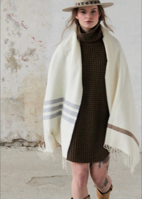 PICTURE OF STOLA LORIGA, MADE IN BEAUTIFUL WOOLWHITE. THE PONCHO IS MADE IN 50% BIO COTTON, 50% BIO WOOL. STRIPED DETAILS IN BEIGE AND (DARK) GREY. DESIGNED BY SCHOOLOFLIFEPROJECTS IN ARNHEM AND PRODUCED IN THE HEART OF PORTUGAL.